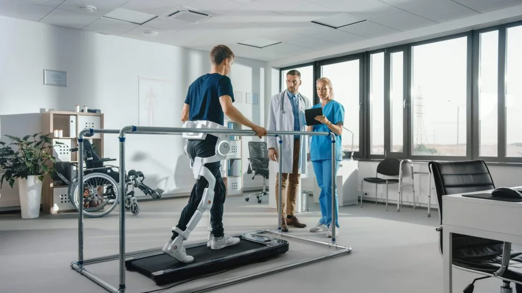 A patient in an exoskeleton walks on a treadmill
