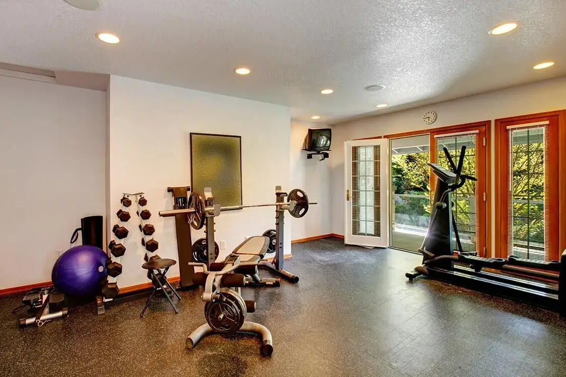 A well-equipped home gym featuring weightlifting gear, benches, and cardio machines